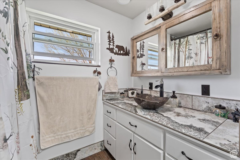 Full bathroom with vanity, wood finished floors, and a healthy amount of sunlight