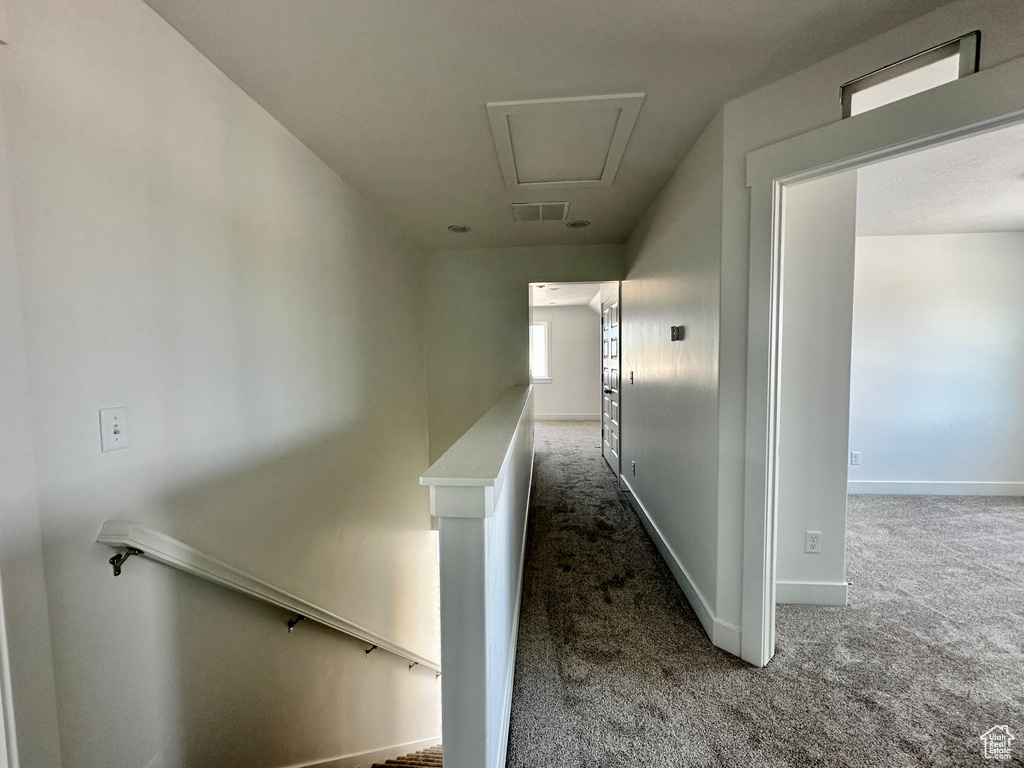 Hallway featuring an upstairs landing, carpet flooring, and attic access