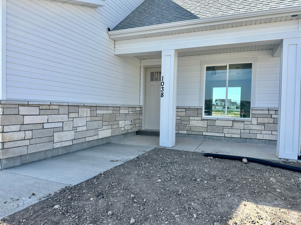 Entrance to property featuring stone siding and a shingled roof