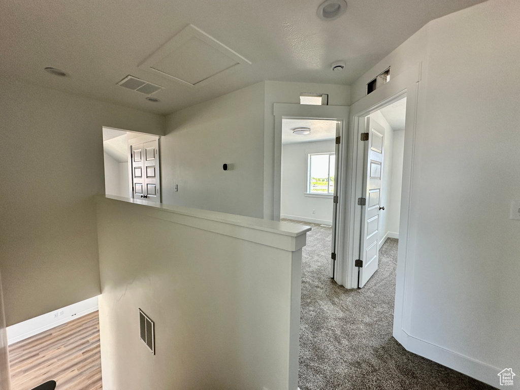 Hall with light colored carpet, an upstairs landing, and attic access