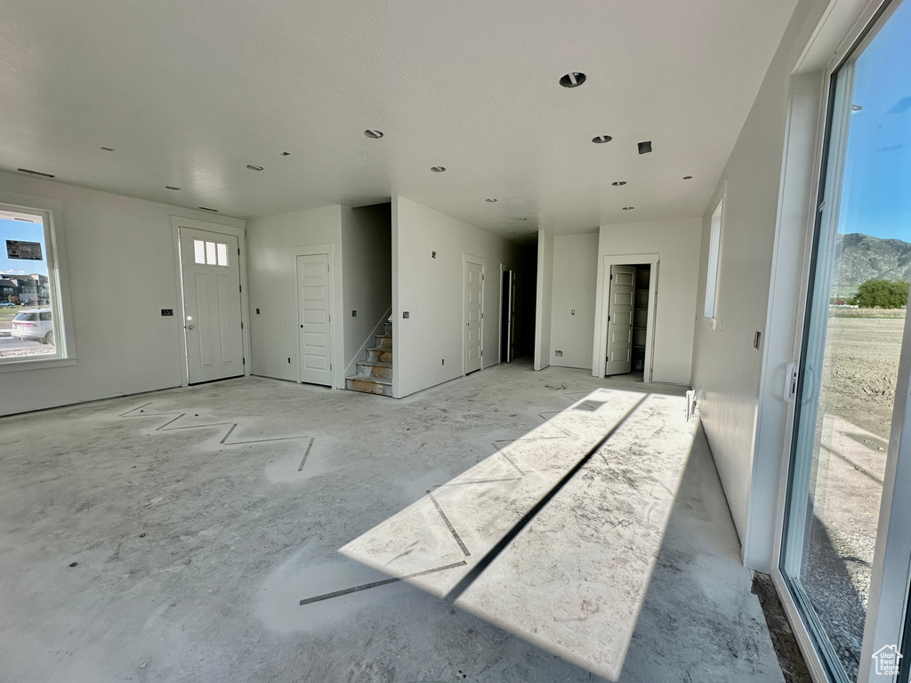 Unfurnished living room featuring stairs and plenty of natural light