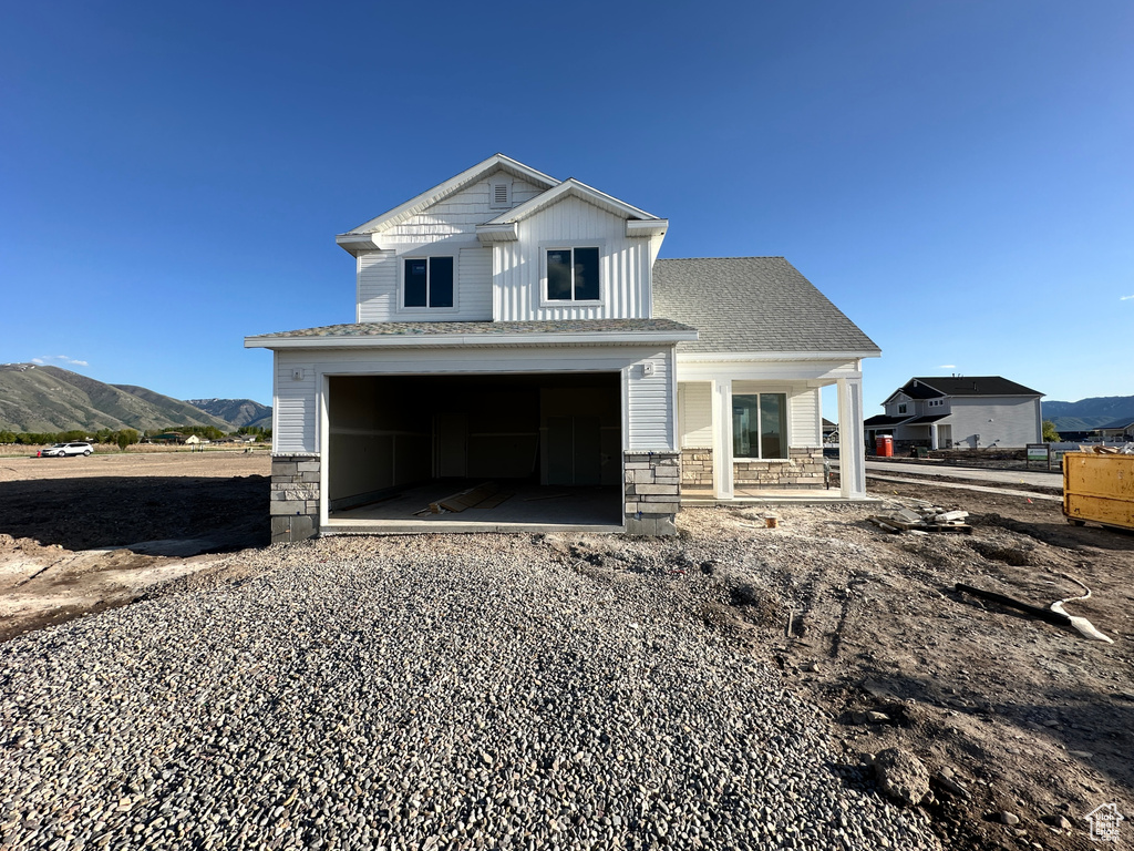 View of front facade with stone siding, a mountain view, a porch, and a garage