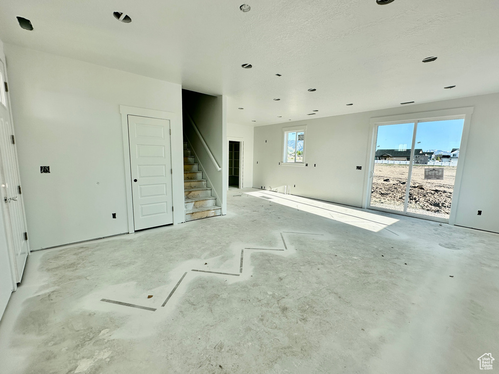 Unfurnished living room with stairs and unfinished concrete floors