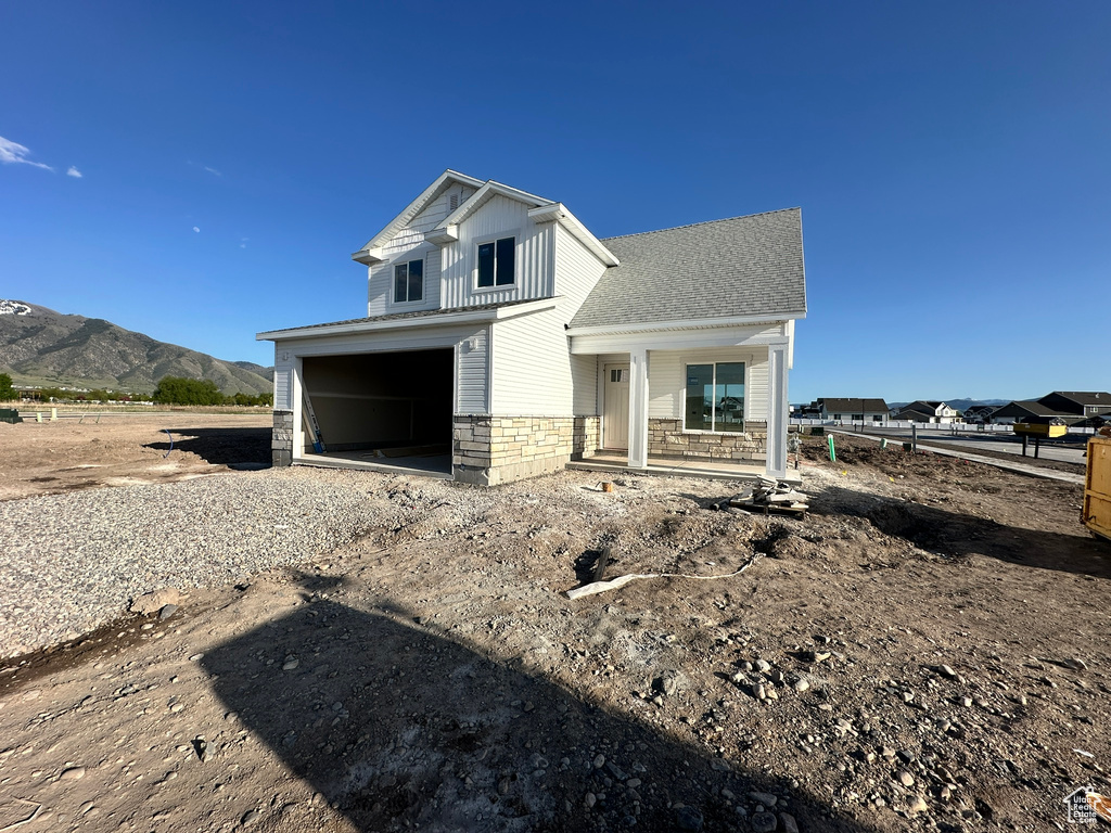 View of front of property with dirt driveway, a garage, a mountain view, and stone siding