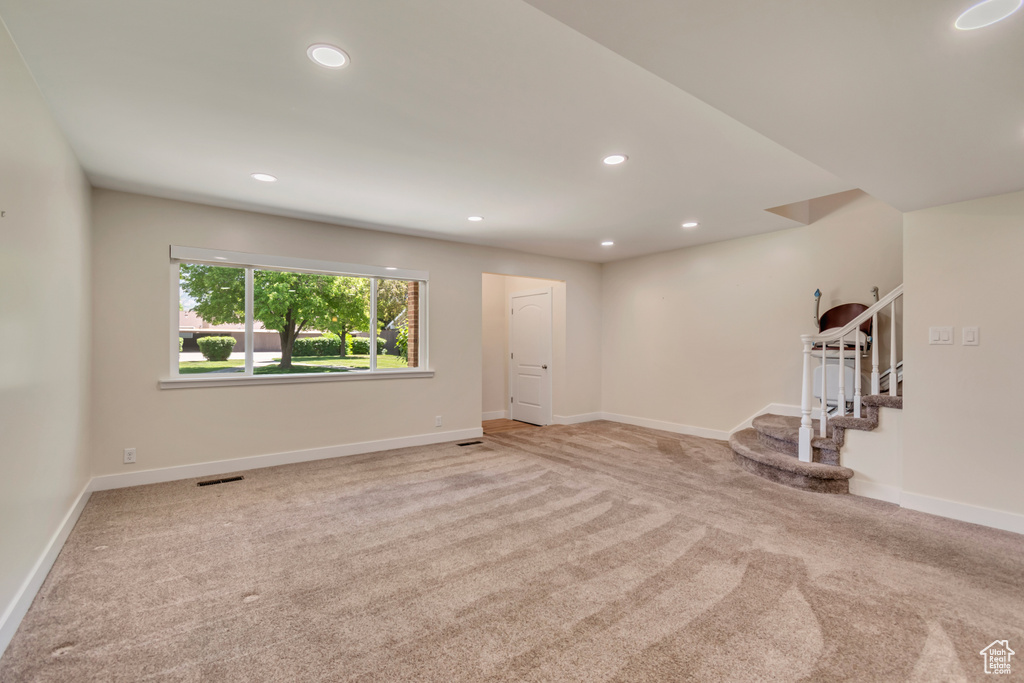 Unfurnished living room featuring carpet floors, stairway, recessed lighting, and baseboards