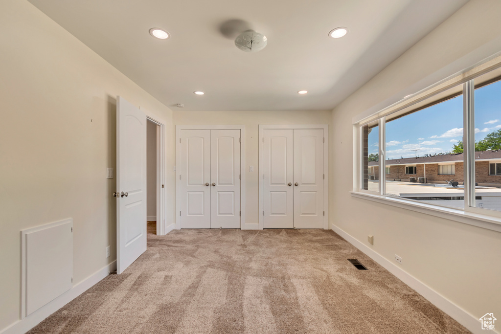 Unfurnished bedroom with multiple closets, light carpet, recessed lighting, and baseboards