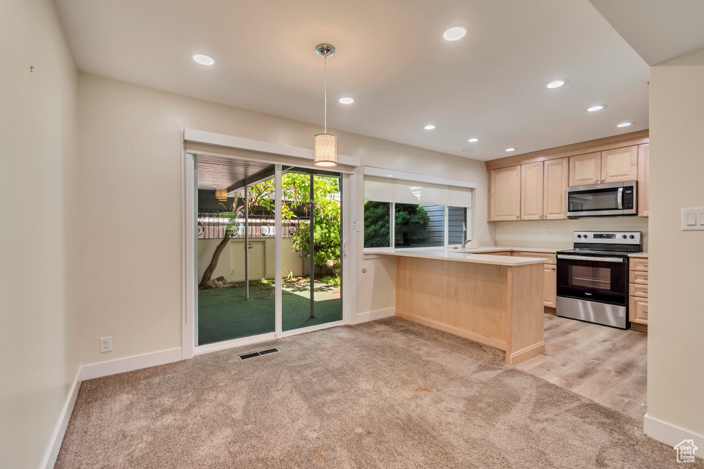 Kitchen with stainless steel appliances, light colored carpet, light brown cabinetry, light countertops, and recessed lighting