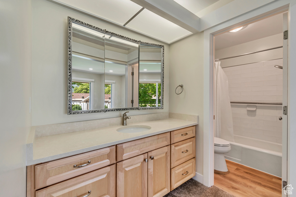 Full bathroom with toilet, vanity, wood finished floors, and shower / tub combo