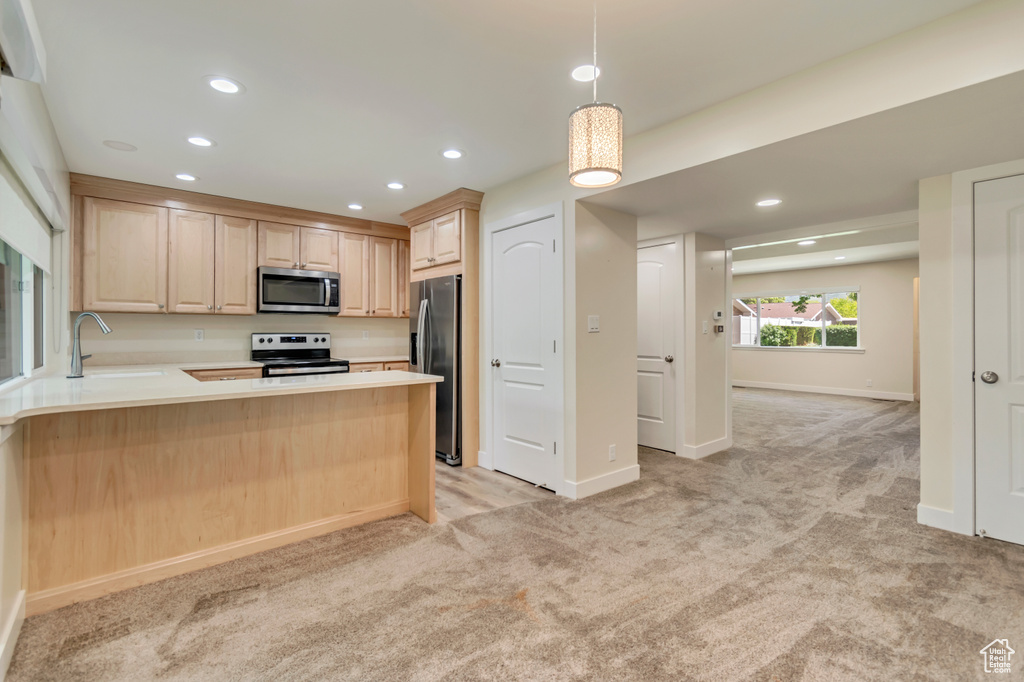 Kitchen featuring appliances with stainless steel finishes, light brown cabinetry, light colored carpet, a peninsula, and recessed lighting
