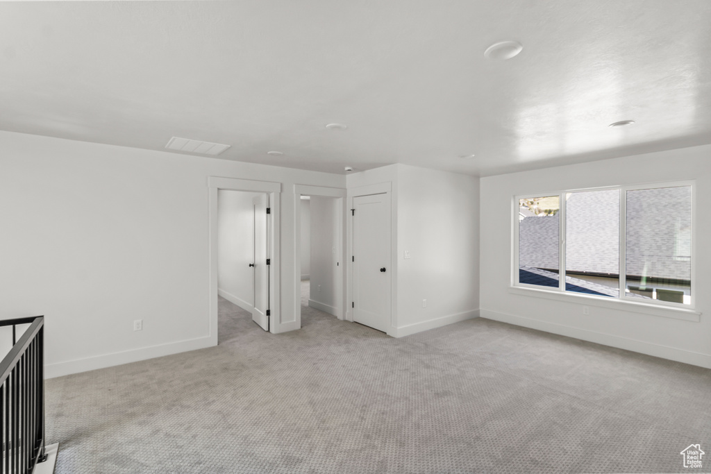 Unfurnished bedroom featuring visible vents, baseboards, and light carpet