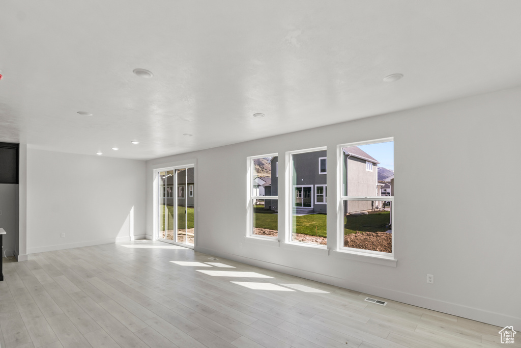 Unfurnished living room featuring visible vents, a wealth of natural light, and light wood-type flooring