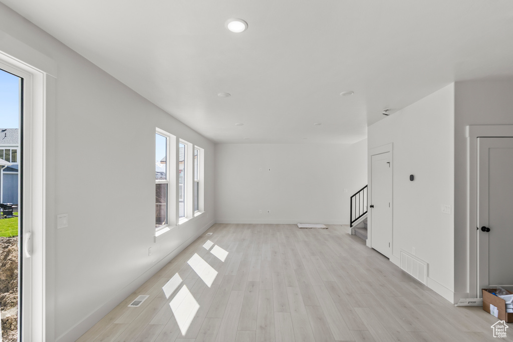 Unfurnished living room featuring visible vents, light wood-type flooring, stairs, and recessed lighting