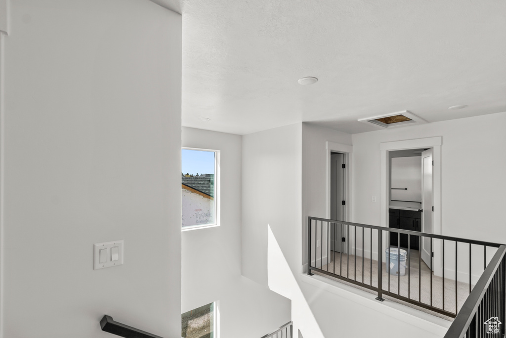 Hallway featuring an upstairs landing and attic access