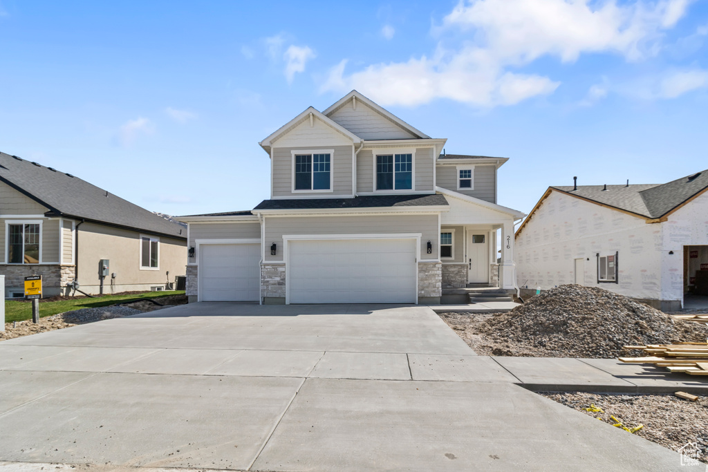 Craftsman house featuring concrete driveway, an attached garage, and stone siding