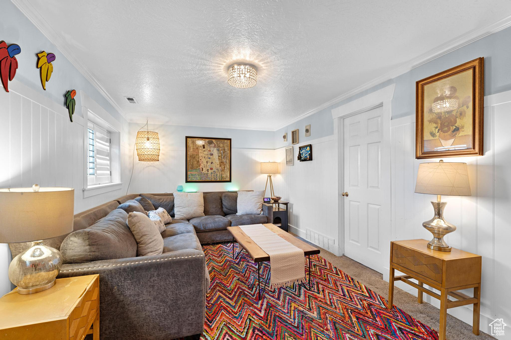 Carpeted living room featuring visible vents, a textured ceiling, and ornamental molding