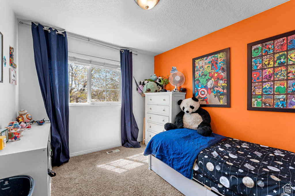 Carpeted bedroom with visible vents and a textured ceiling