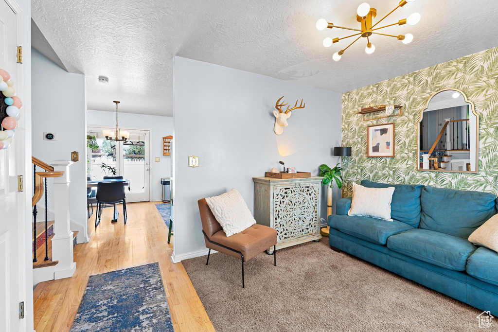 Living area featuring wallpapered walls, an accent wall, a notable chandelier, and wood finished floors