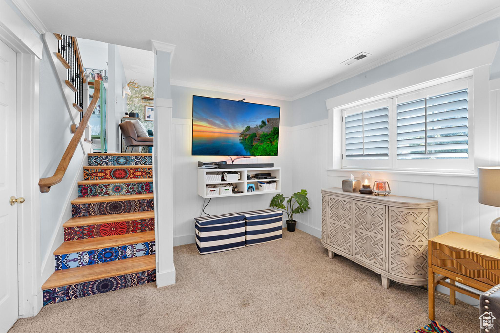 Carpeted living room featuring visible vents, a wainscoted wall, stairway, and a textured ceiling