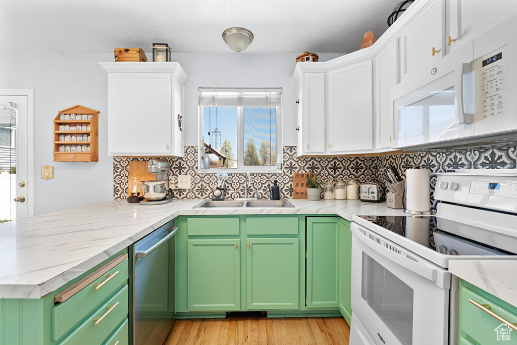 Kitchen with a wealth of natural light, white cabinetry, and white appliances