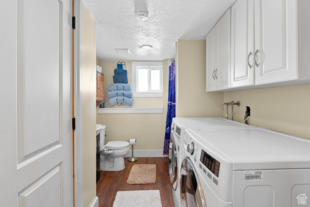 Washroom featuring laundry area, dark wood-type flooring, a textured ceiling, baseboards, and washer and clothes dryer