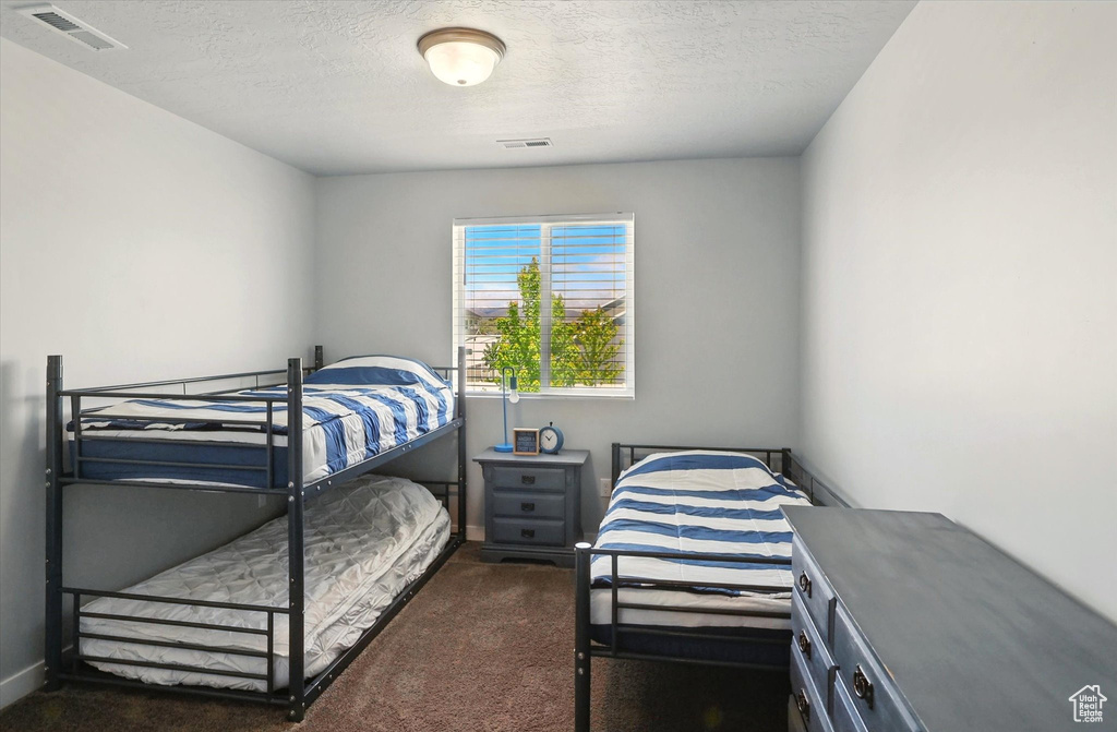Bedroom with dark colored carpet, a textured ceiling, and baseboards
