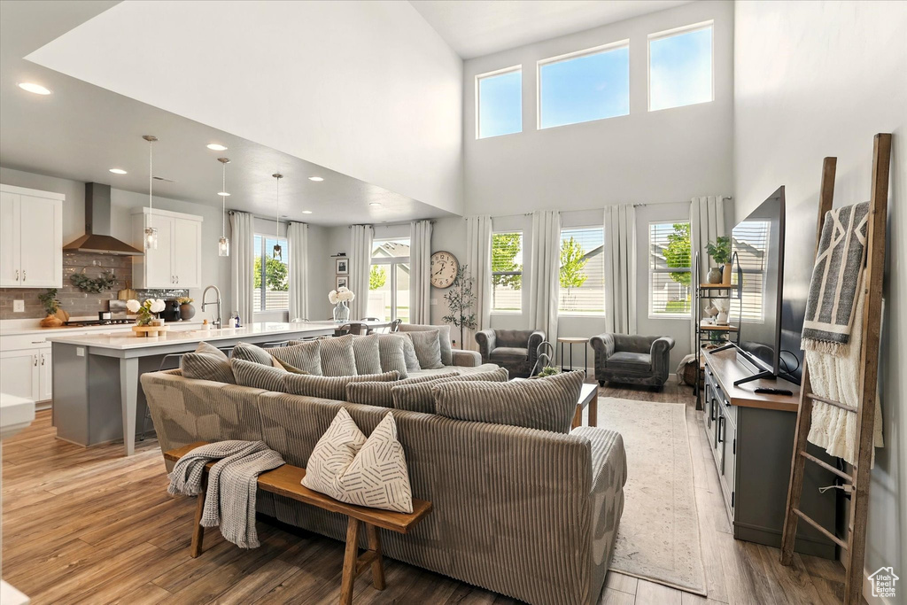 Living area with light wood finished floors, recessed lighting, and a towering ceiling