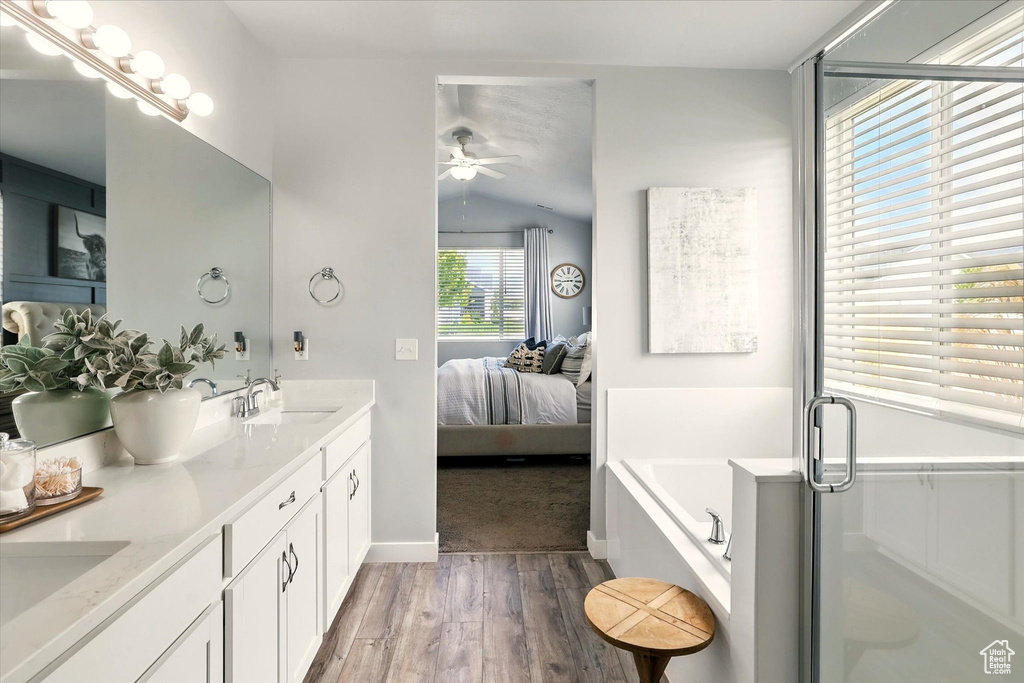 Bathroom with ensuite bathroom, wood finished floors, ceiling fan, a garden tub, and double vanity