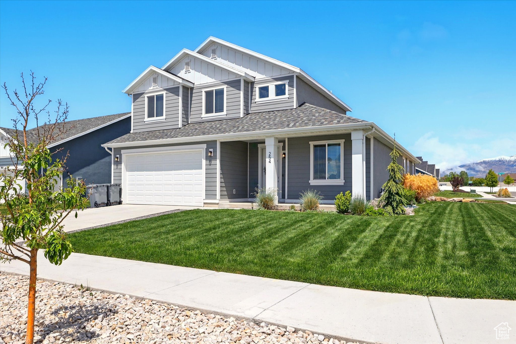 View of front of property featuring driveway, an attached garage, a front yard, board and batten siding, and a mountain view