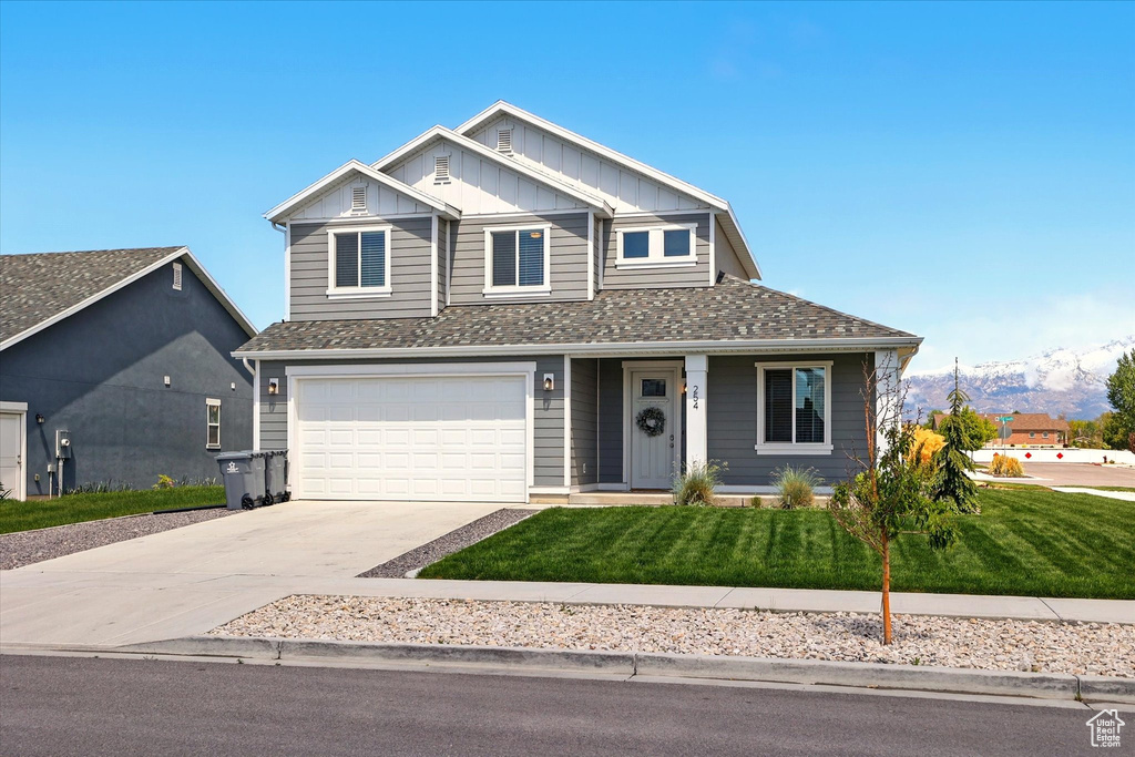 Craftsman-style house featuring board and batten siding, driveway, an attached garage, and a front yard