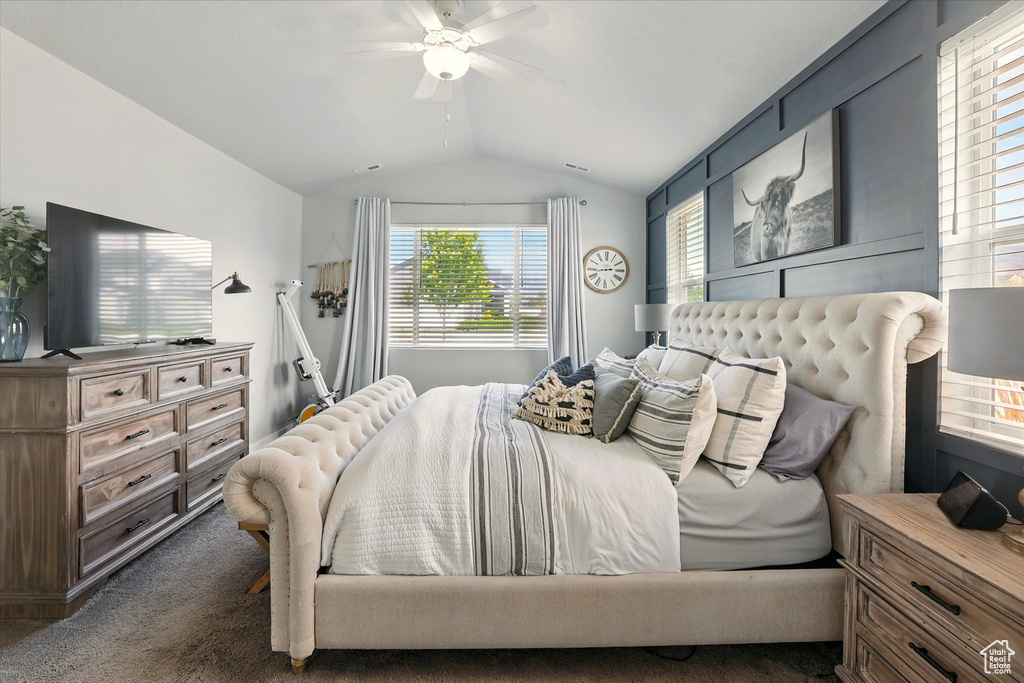 Carpeted bedroom featuring vaulted ceiling and ceiling fan