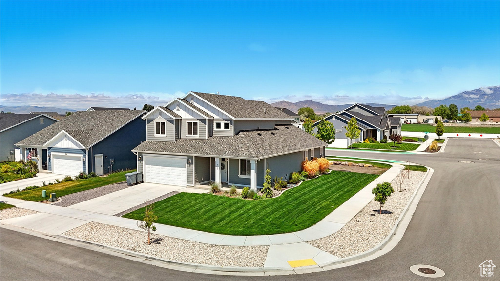 Traditional-style home featuring a residential view, concrete driveway, a front lawn, and a mountain view