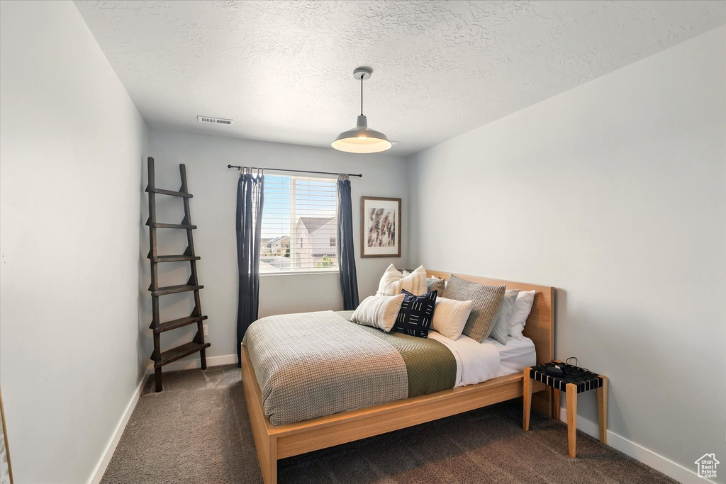 Bedroom with carpet flooring, baseboards, and a textured ceiling