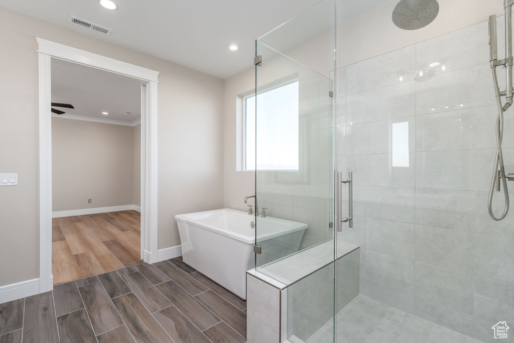 Bathroom featuring a stall shower, a freestanding tub, recessed lighting, wood finished floors, and baseboards