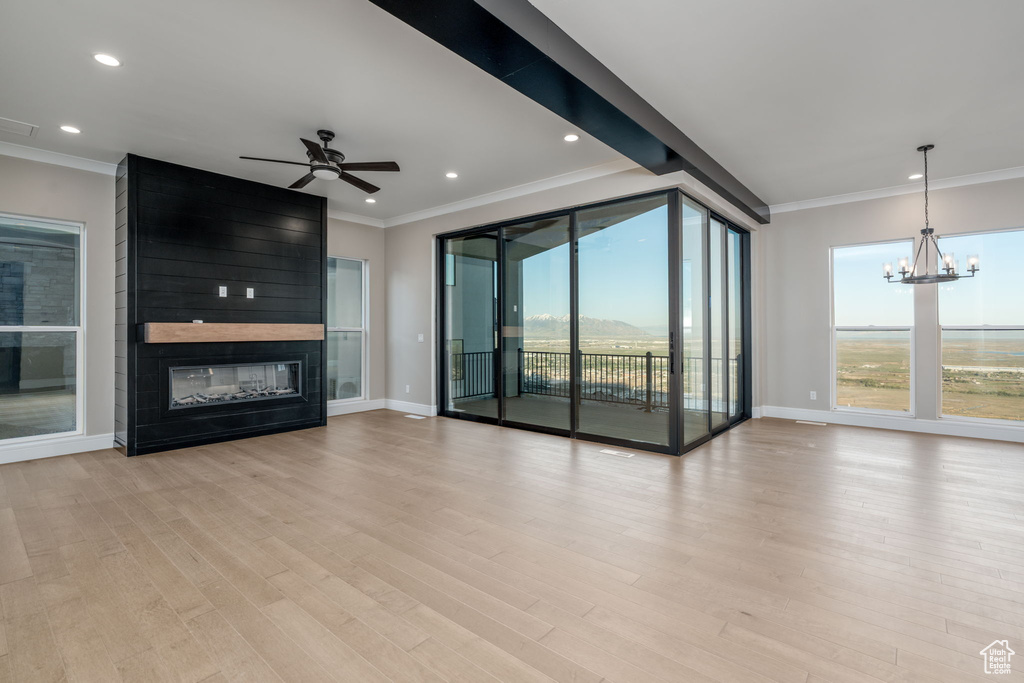 Unfurnished living room with crown molding, ceiling fan, a large fireplace, baseboards, and light wood-type flooring