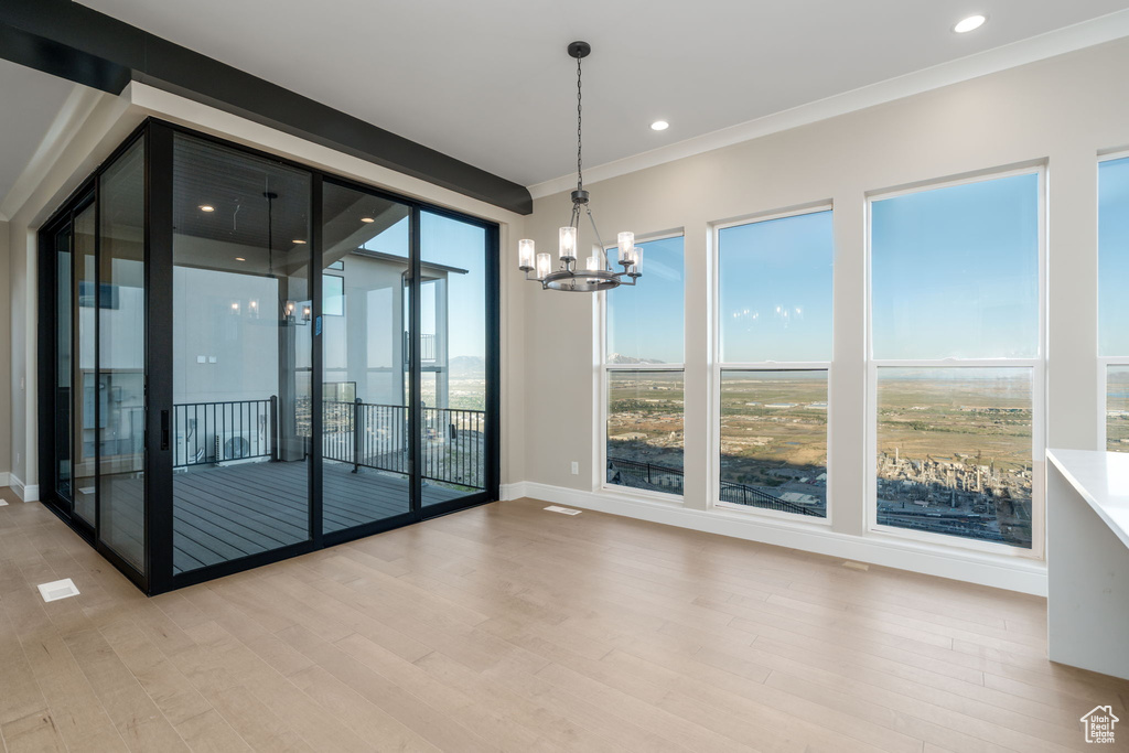 Spare room featuring a chandelier, light wood-style floors, ornamental molding, baseboards, and recessed lighting