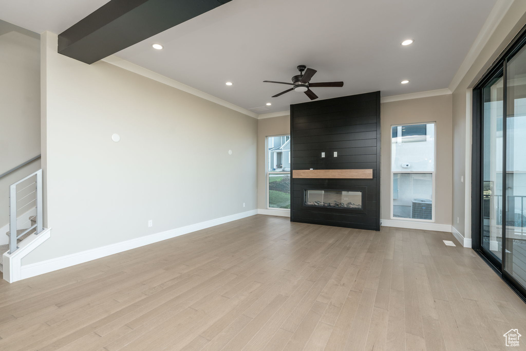 Unfurnished living room with crown molding, light wood finished floors, baseboards, a ceiling fan, and a fireplace