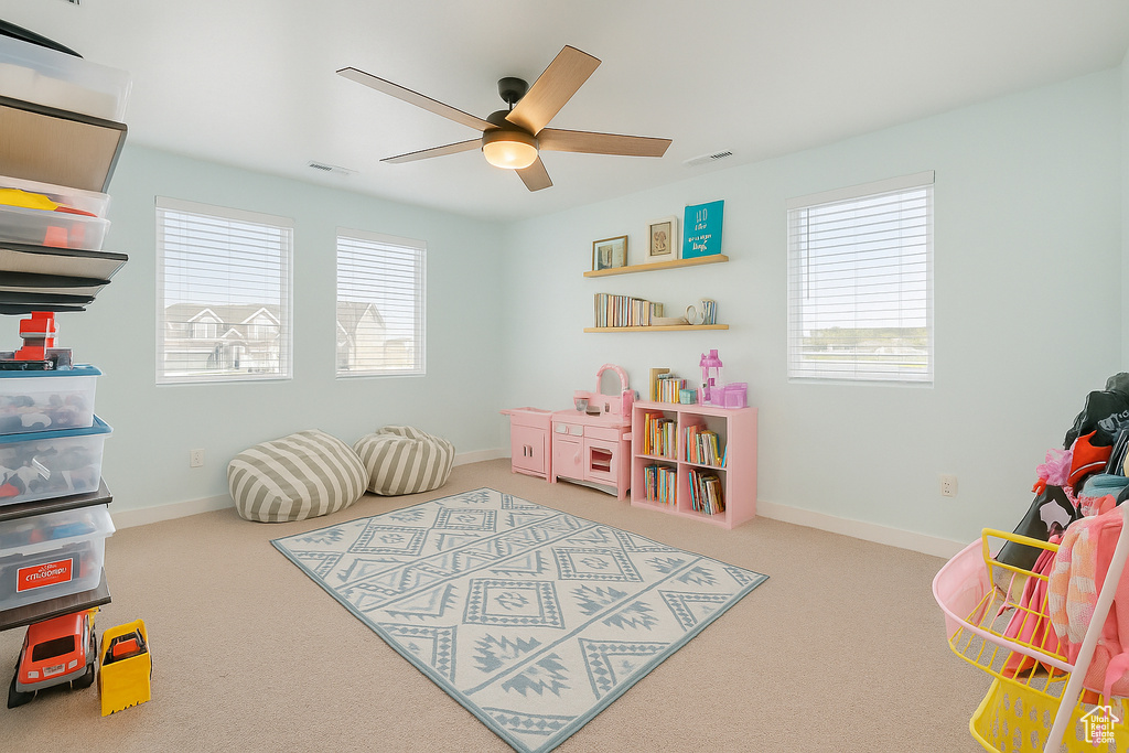 Rec room featuring carpet flooring, a ceiling fan, and a healthy amount of sunlight