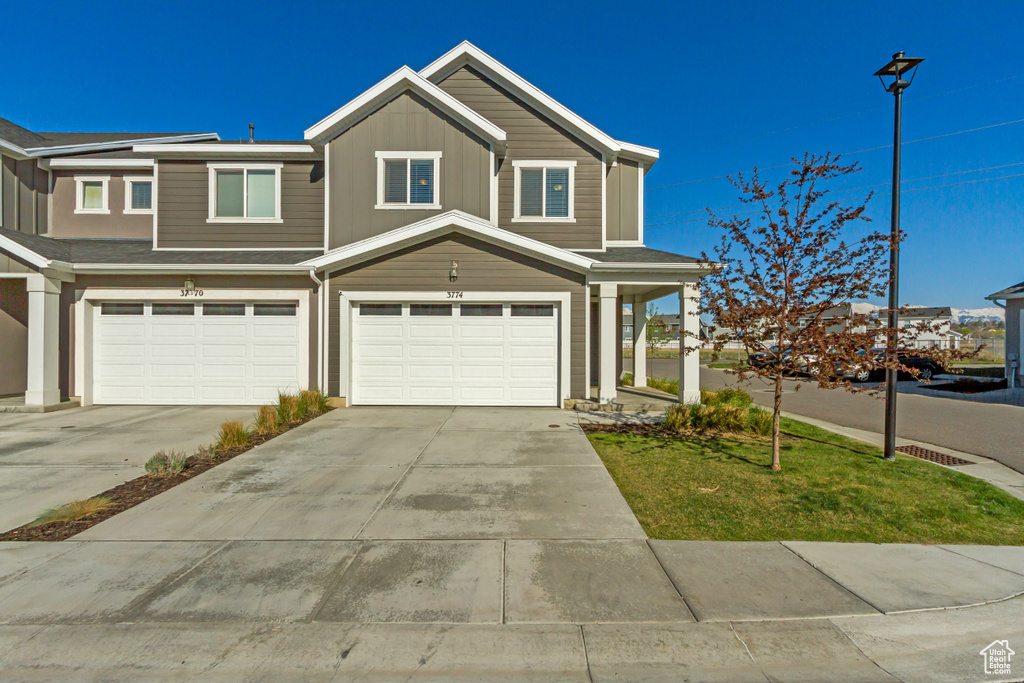 View of front facade with an attached garage, board and batten siding, and concrete driveway