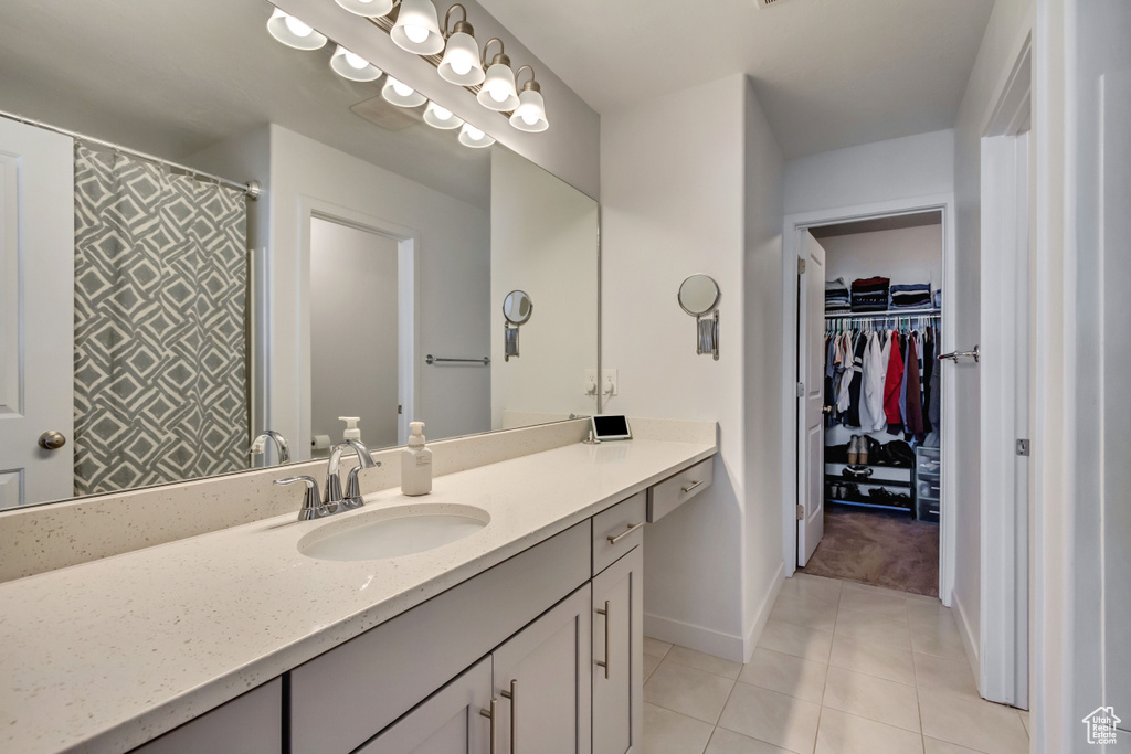 Full bath with vanity, baseboards, curtained shower, a spacious closet, and tile patterned flooring