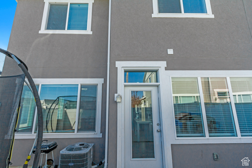 Entrance to property with stucco siding and central air condition unit