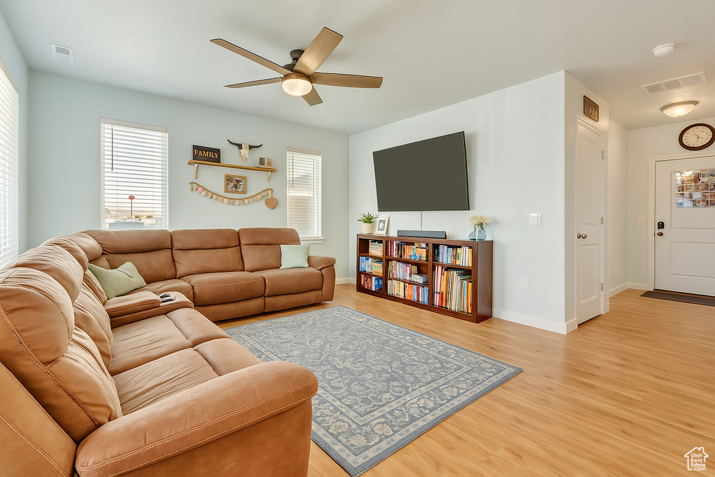 Living area with visible vents, a ceiling fan, a wealth of natural light, and light wood-type flooring
