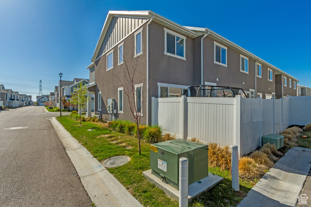 View of side of home featuring fence, a residential view, and stucco siding