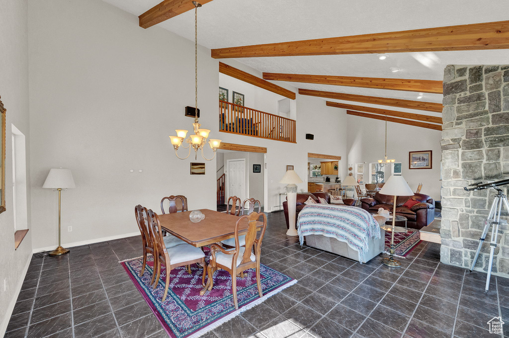 Dining area with beamed ceiling, an inviting chandelier, baseboards, and high vaulted ceiling