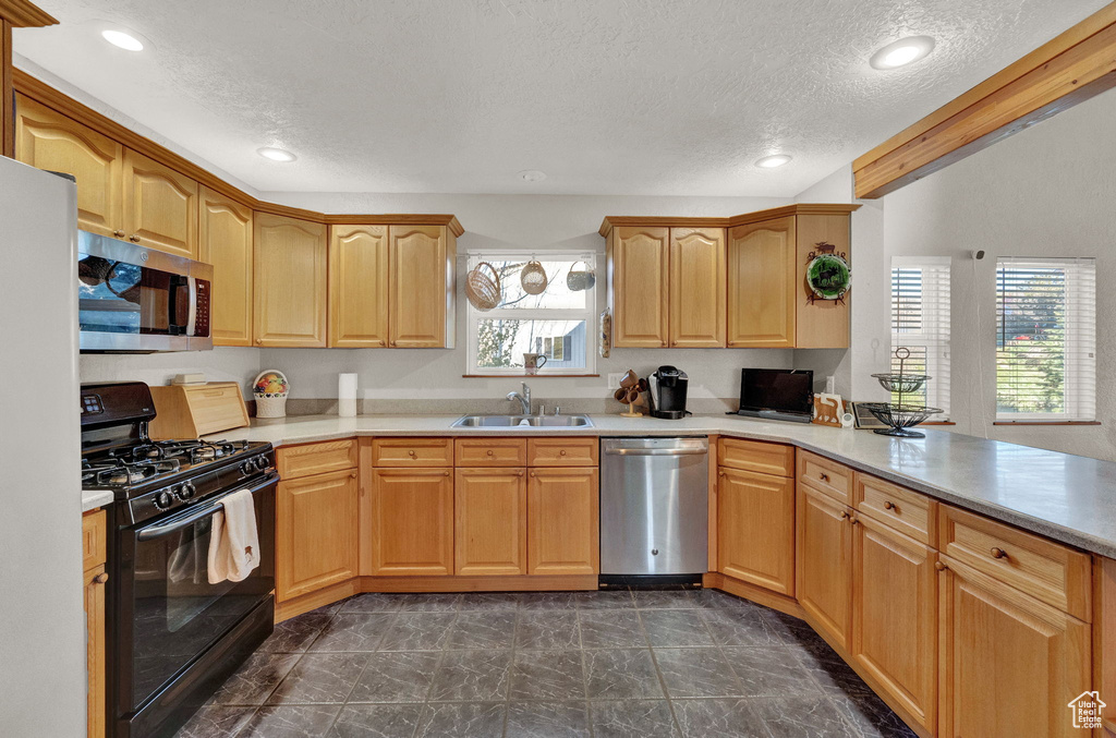 Kitchen with a textured ceiling, a sink, light countertops, marble finish floor, and stainless steel appliances