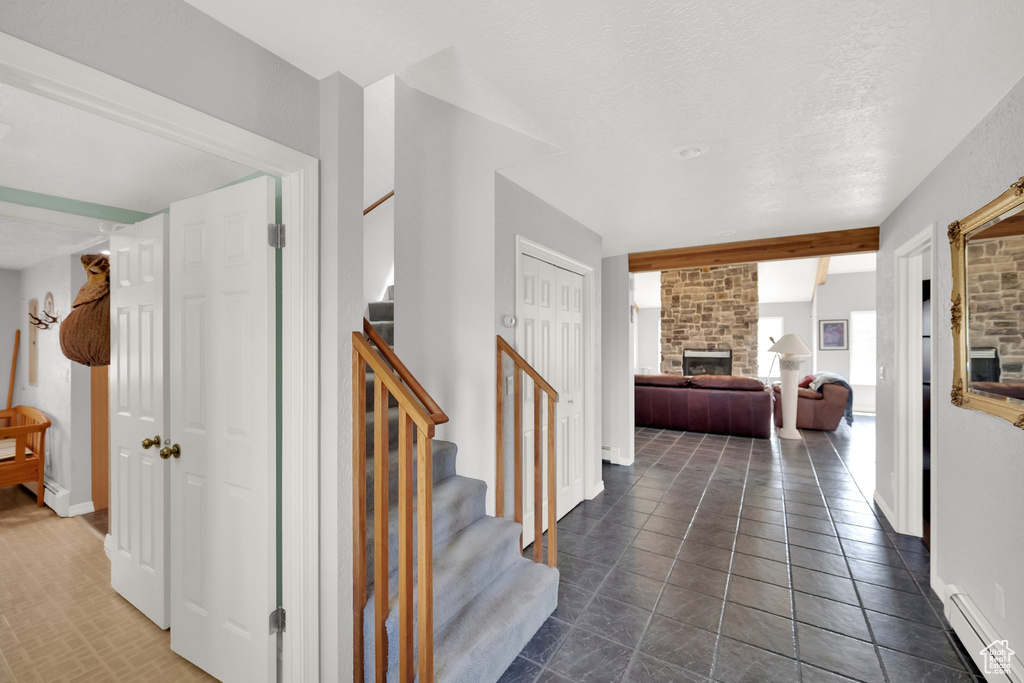Corridor with stairway, baseboards, a baseboard radiator, and dark tile patterned floors