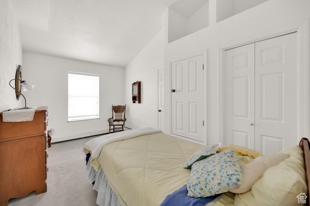 Carpeted bedroom featuring a closet, a baseboard radiator, and vaulted ceiling