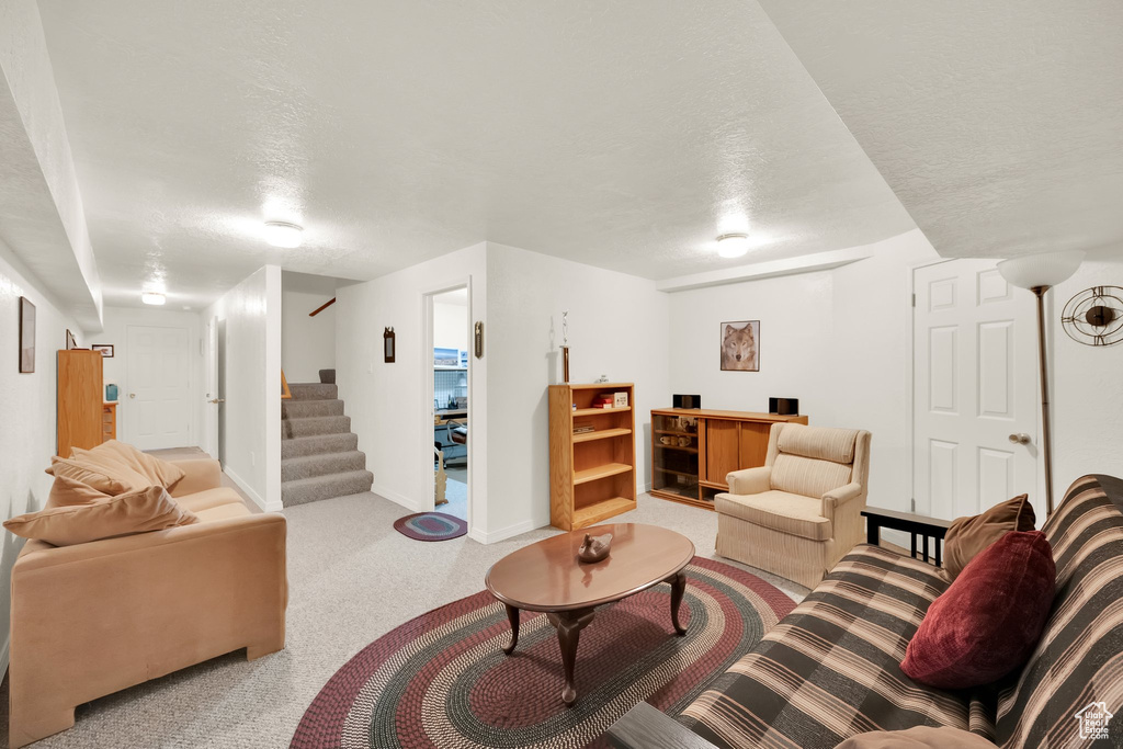 Carpeted living room with baseboards, a textured ceiling, and stairway