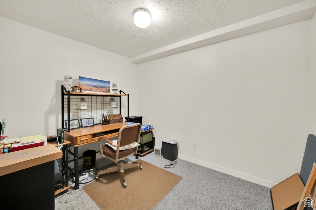 Carpeted office featuring baseboards and a textured ceiling