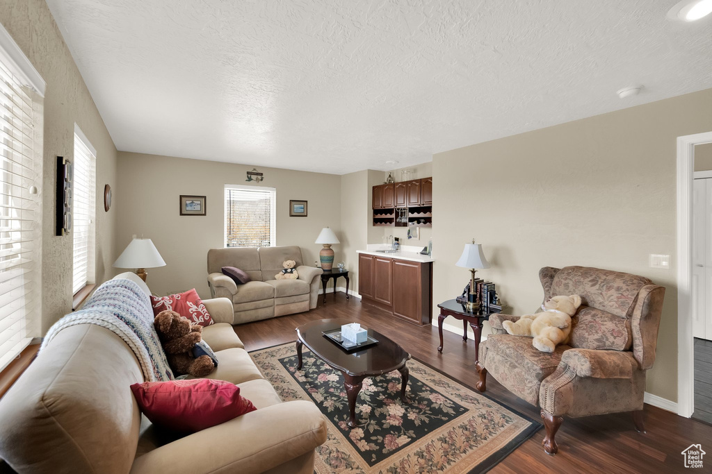 Living area featuring dark wood-type flooring, a textured ceiling, and baseboards