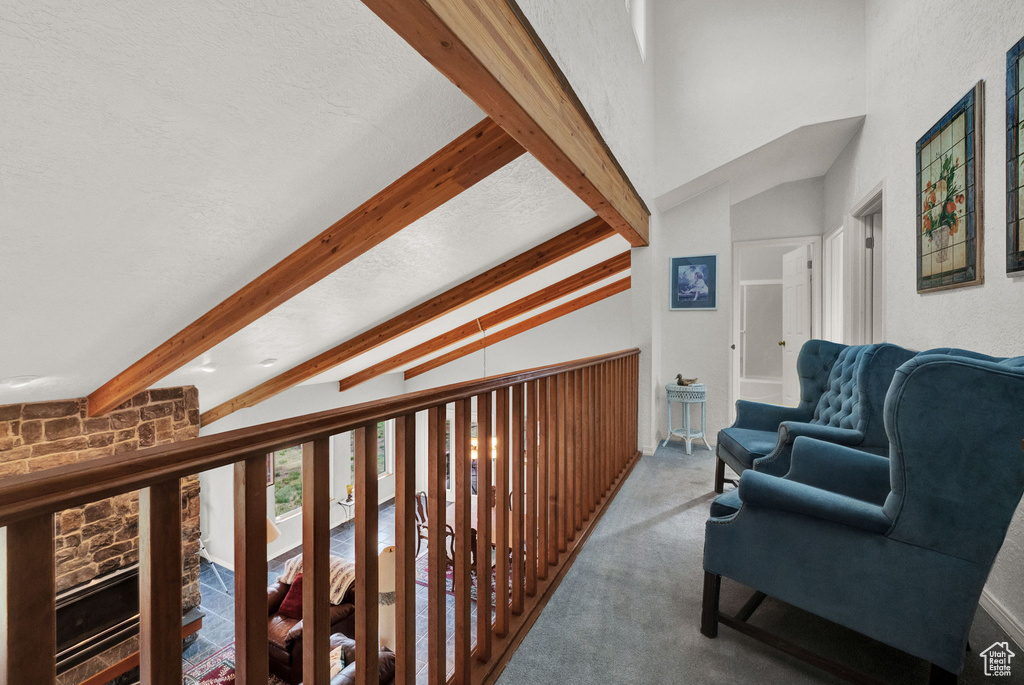 Corridor with a textured ceiling, beam ceiling, and carpet